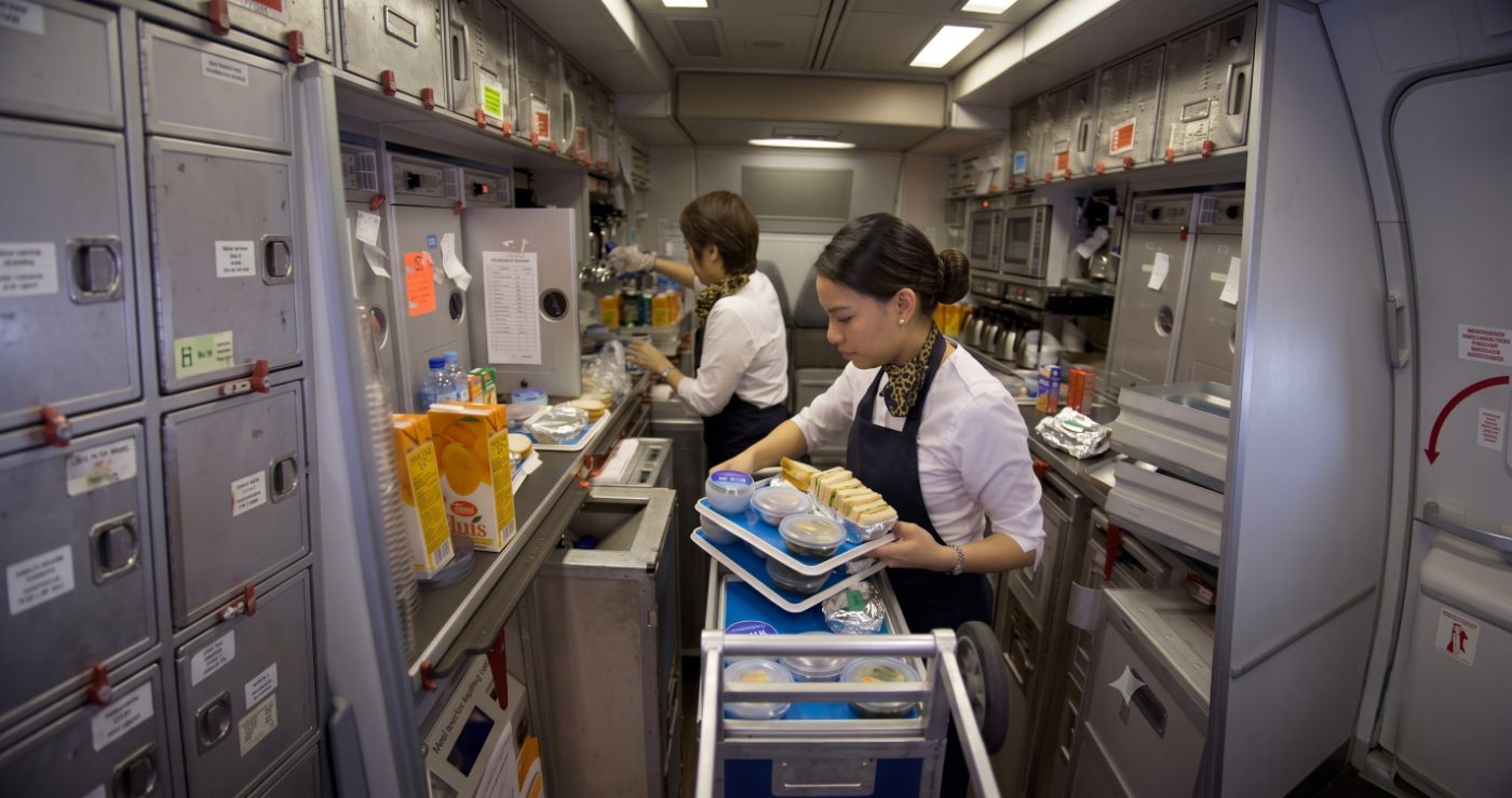 Cabin crew loading meal trays in an aircraft galley