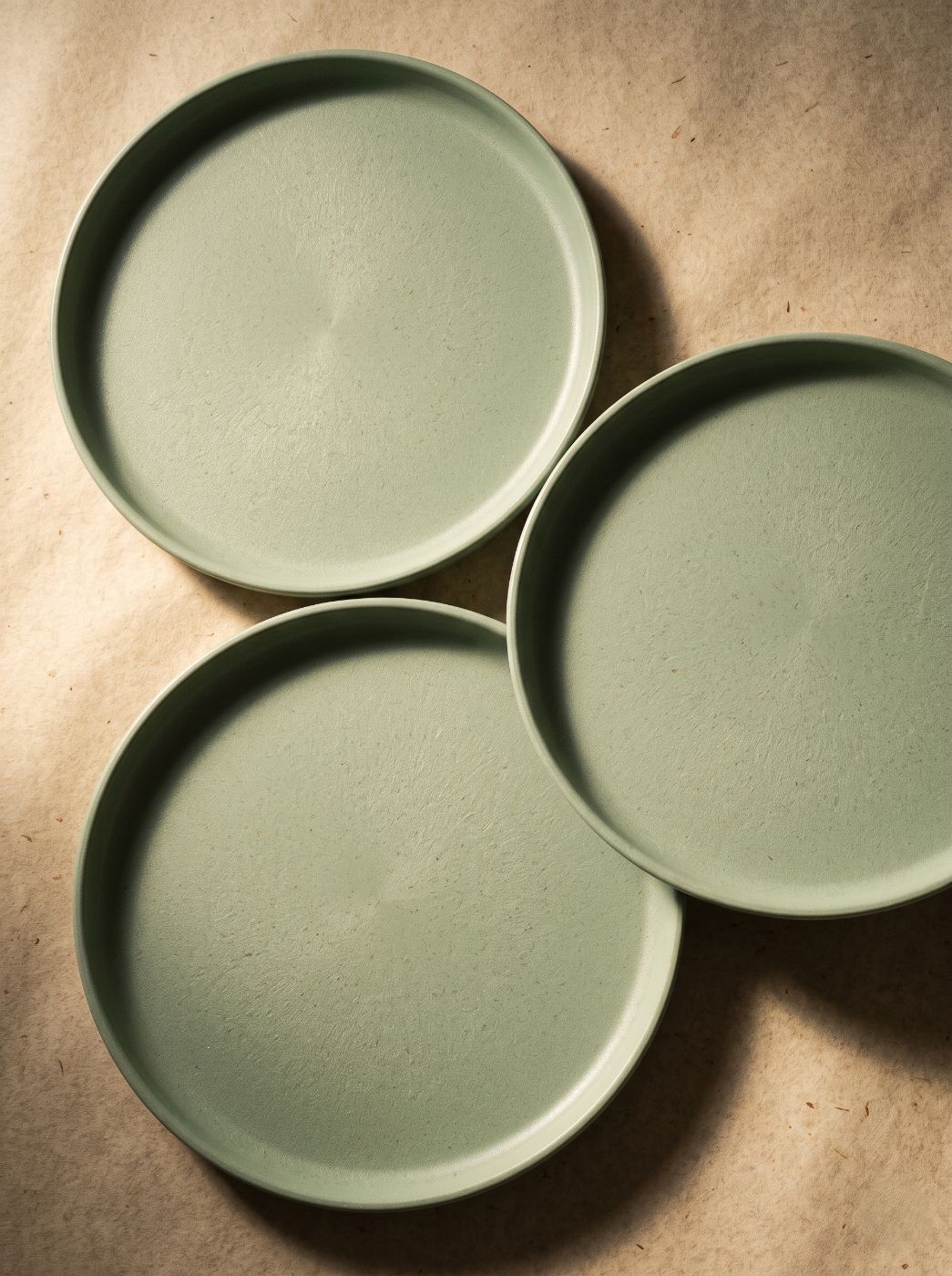 Three sage bio-composite coupe plates showing the textured surface